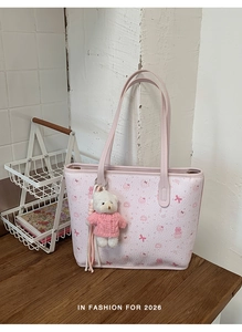 Detail of pink cartoon tote bag with leather texture and plush bear charm accessory