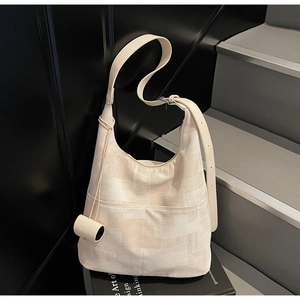 Close-up of beige tote bag with geometric pattern and decorative cylindrical pendant