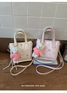 Detail of cream and pink tote bags featuring cute cartoon prints and plush bear charms