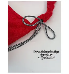 Detail of red plush bucket bag featuring an adjustable black and white woven drawstring bow