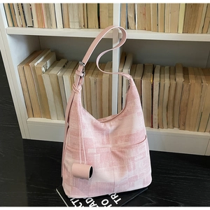 Pink tote bag detail with geometric texture, adjustable strap and hanging charm decoration