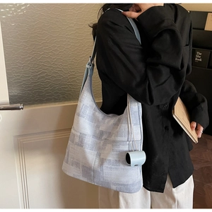 Close-up of light blue canvas hobo bag with geometric pattern and adjustable strap on model