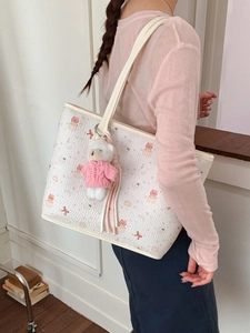 Cute white tote bag with cartoon cat print and plush bear charm shown on model
