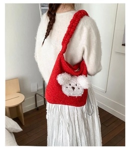 Close-up of red plush bucket bag with cute 3D teddy bear charm and soft fuzzy texture