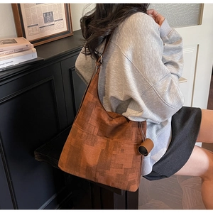 Brown vintage textured tote bag with geometric patterns and cylindrical charm detail
