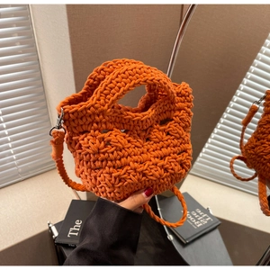 Detail of orange hand-knitted crossbody bag showing thick honeycomb texture and strap