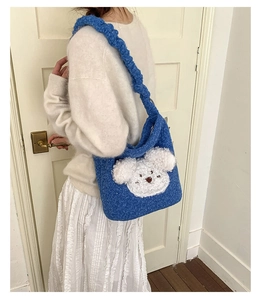 Close-up of blue plush puppy bucket bag with woven strap and fluffy texture detail