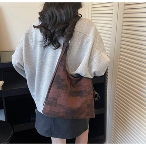 Detail shot of large brown canvas tote bag with square pattern texture on shoulder
