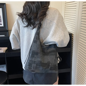 Detail of dark grey tote bag with geometric patchwork texture and slim shoulder strap