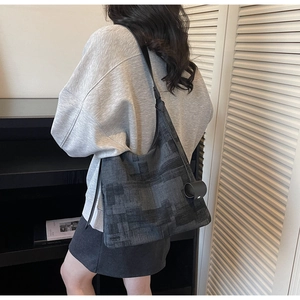 Detailed view of grey geometric textured tote bag worn as a shoulder bag on a model