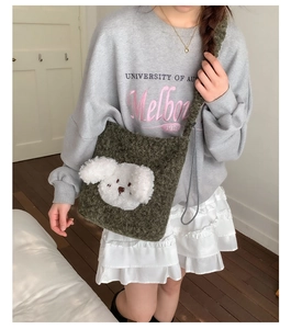 Detail of dark green plush bucket bag featuring a cute 3D white puppy face and cord strap