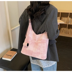 Pink textured tote bag with cylindrical charm shown in a minimalist interior setting