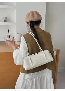 Borsa a spalla retrò francese in pelle lucida bianca indossata da una modella per il giorno
