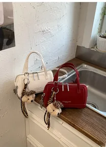 Detail of Boston-style handbags in beige and red with plush puppy charm and brand logo