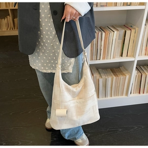 Detail of minimalist cream canvas tote bag with front pocket and cylindrical charm