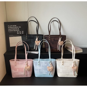 Five colored tote bags with geometric texture and cute teddy bear charms on a modern setup