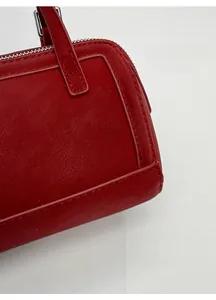 Close-up of red pebbled leather texture with silver zipper and fine stitching details
