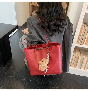 Detalle del bolso tote rojo de cuero PU con un lindo oso de peluche marrón y texto en dorado