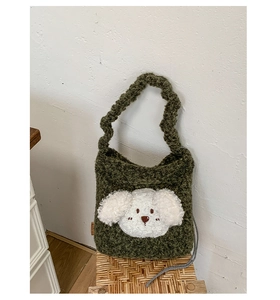 Detailed view of green plush bucket bag with cute white 3D puppy patch on a wicker stool
