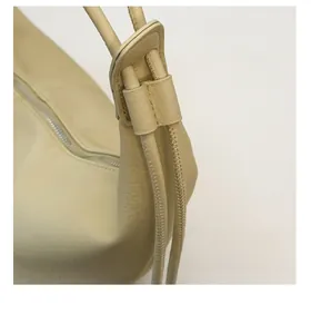 Close-up of adjustable knotted shoulder strap and silver zipper on beige leather bag