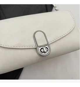 Gros plan d'un sac à main en cuir blanc avec un fermoir rotatif argenté aux textures ondulées