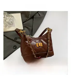 Detailaufnahme der dunkelbraunen Stepptasche mit goldenem Kettengurt und Drehverschluss