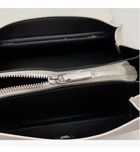 Détail du zip en métal argenté et de la doublure noire sur un sac en cuir blanc