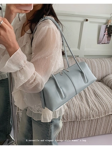 Primo piano di una borsa baguette vintage in pelle celeste indossata da una modella