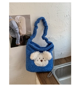 Detailed close-up of Klein blue plush bucket bag with cute 3D puppy motif and ruffled strap
