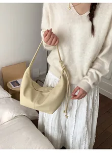 Close-up of beige moon-shaped hobo bag featuring knotted shoulder strap and soft leather texture