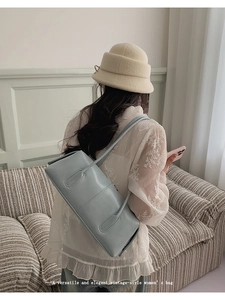 Minimalist light blue faux leather tote bag being carried over the shoulder in a bright room