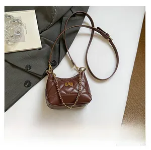 Mini-Stepptasche in Kaffeebraun mit Kette neben Smartphone zum Größenvergleich