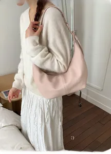 Close-up of pink lychee grain leather crescent bag styled with a white mohair sweater