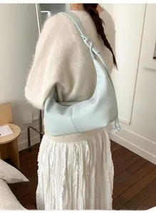 Detail of light blue crescent shoulder bag with drawstring knot and leather texture