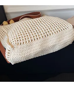 Detail of hollow knit mesh texture on off-white tote bag with brown leather strap