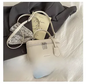 Détail du sac boîte crème présenté à côté d'un smartphone pour comparer la taille