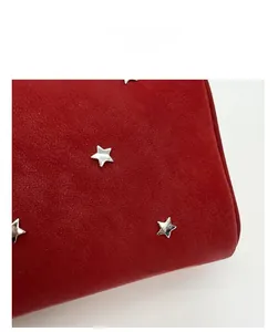 Close-up of red suede handbag featuring silver metal star rivets and soft texture