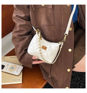 Détail d'un sac blanc matelassé avec fermoir rotatif doré et bandoulière chaîne élégante