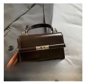 Detailed close-up of dark brown glossy patent leather bag with a metal lock buckle and handle