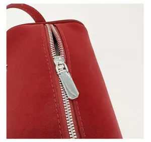 Close-up of silver metal zipper and red suede texture on stylish commuter handbag