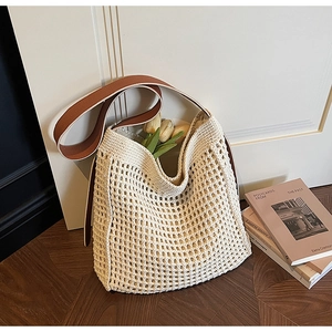 Detail of cream woven mesh beach bag with a wide dark brown leather shoulder strap