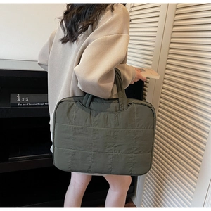 Close-up of a minimalist dark green quilted tote bag with smooth nylon texture