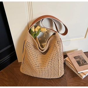 Macro view of khaki hollow-out woven tote bag with a premium brown leather shoulder strap