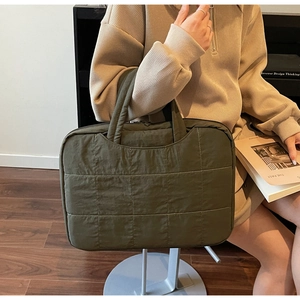 Detailed close-up of dark green quilted laptop tote bag with sturdy top handles