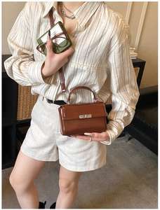 Close-up of a brown patent leather handbag with a silver rectangular twist lock