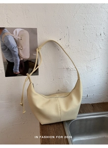 Detail of light yellow hobo bag with pebble leather texture and vertical stitching