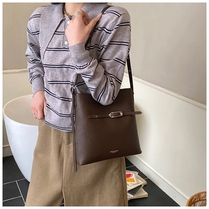 Gros plan détaillé du sac seau en cuir marron foncé avec boucle et logo de marque