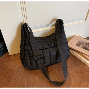 Gros plan du sac bandoulière matelassé noir avec motif à carreaux et large sangle en nylon