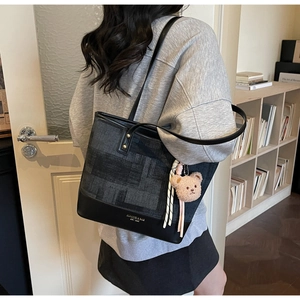 Dettaglio della grande borsa tote grigia con ciondolo a forma di orso rosa sulla spalla
