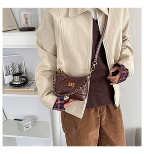 Détail d'un sac bandoulière marron foncé matelassé avec fermoir doré en métal